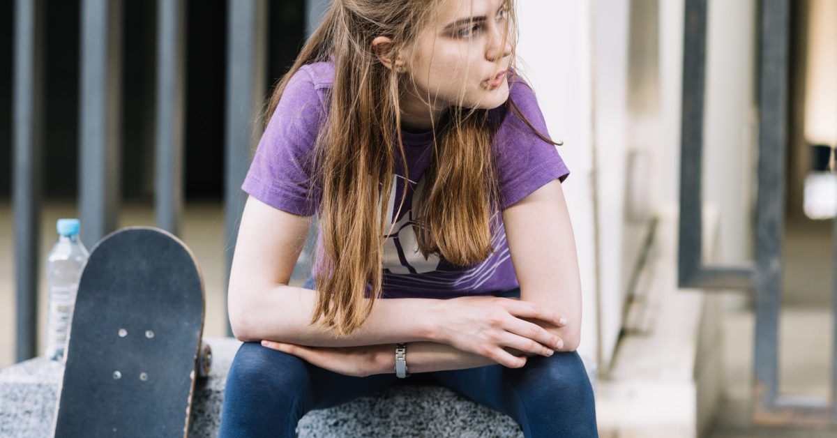 skateboarder-girl-sits-with-her-skateboard-biting-her-lip
